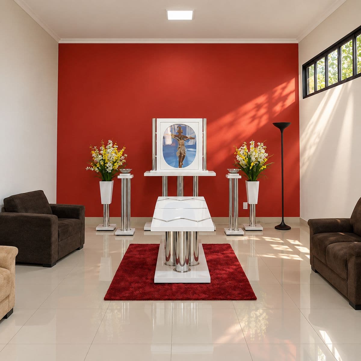 Interior da capela da Pax Vida, com o esquife branco sobre o tapete vermelho, arranjos de flores, o crucifixo ao fundo e sofás para a família