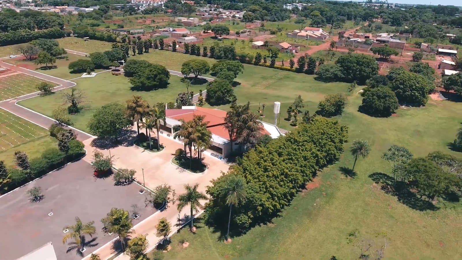 Vista aérea do Cemitério Parque Monte das Oliveiras, em Campo Grande, com alamedas arborizadas, estacionamento e o prédio da administração